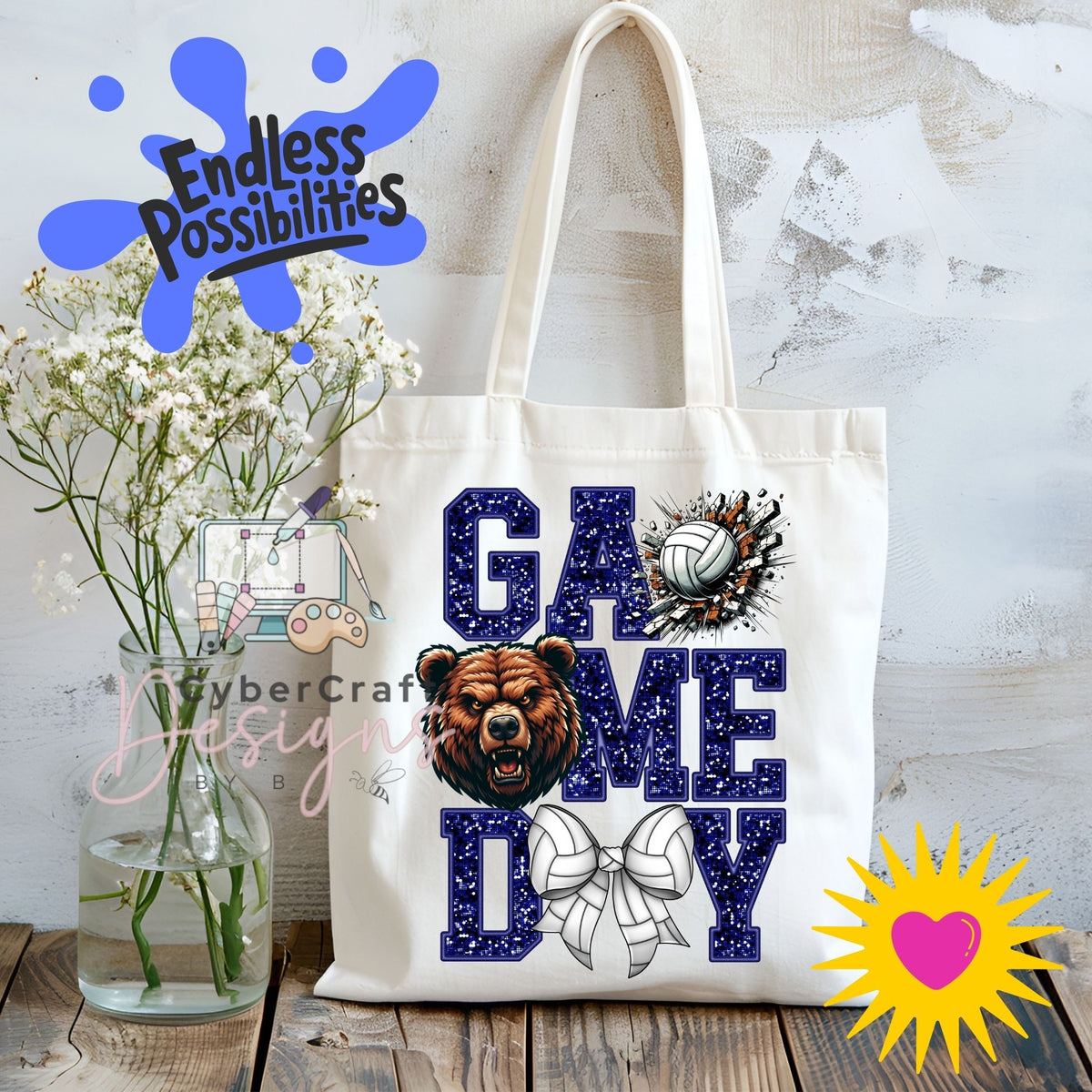 A white canvas tote bag with 'GAME DAY' printed in navy blue glitter-style letters, featuring a bear head graphic, volleyball, and bow design. The bag is displayed on a wooden surface next to a vase of white flowers, with decorative digital overlays including 'Endless Possibilities' and 'CyberCraft Designs'.