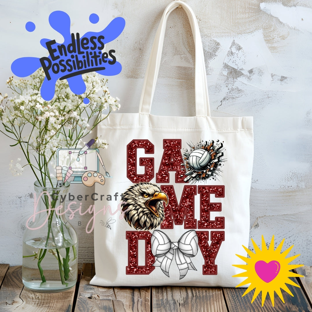 A white canvas tote bag with a 'Game Day' graphic featuring a bald eagle, volleyball, and bow tie, displayed on a rustic wooden table with baby's breath flowers and decorative overlays.
