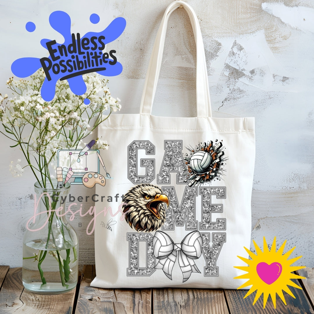 A white canvas tote bag with a custom graphic design featuring the words 'GAME DAY' in a glittery gray font, decorated with an eagle head illustration, a volleyball, and a bow. The bag is displayed on a rustic wooden table next to a glass vase of white flowers, with decorative digital overlays including 'Endless Possibilities' and 'CyberCraft Designs'.