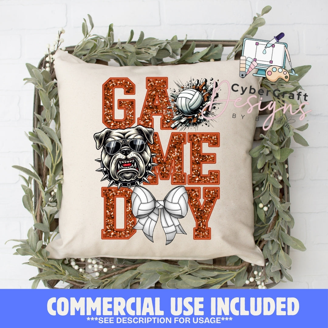 A square beige throw pillow displayed in a rustic wooden crate with green foliage, featuring a 'GAME DAY' design with a bulldog, volleyballs, and glitter-textured lettering. A blue banner at the bottom reads 'COMMERCIAL USE INCLUDED'.
