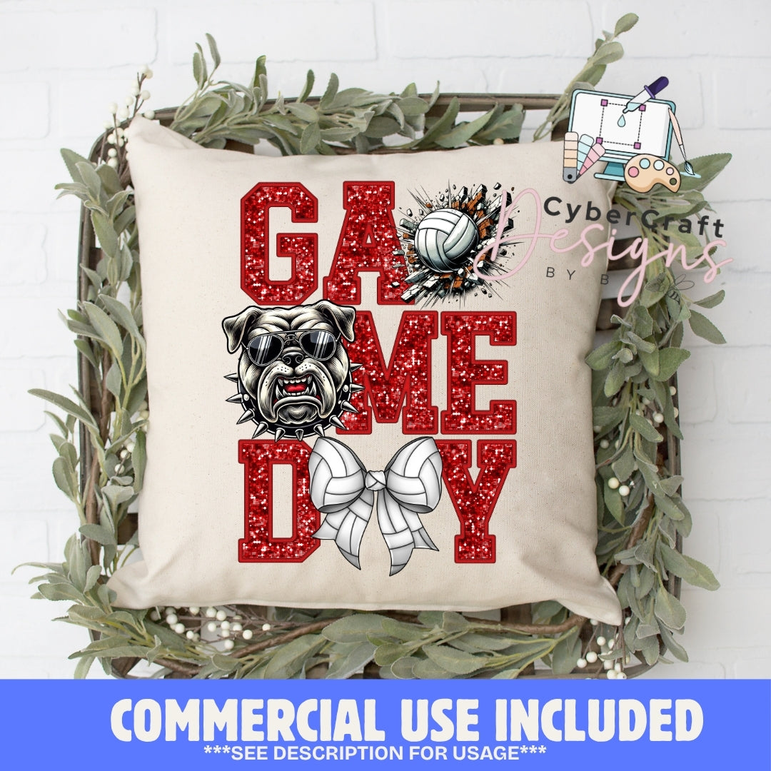A square beige throw pillow with a 'Game Day' graphic featuring red glitter-textured letters, a bulldog illustration, a volleyball, and a volleyball bow. The pillow is displayed in a rustic wooden crate decorated with green foliage, set against a white brick wall background.