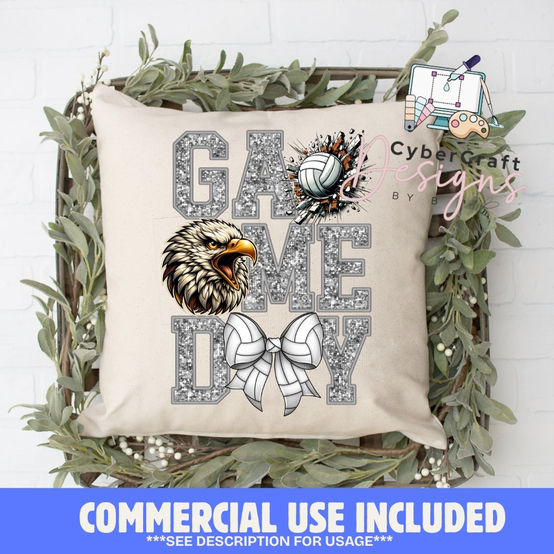 A square beige throw pillow displayed in a decorative wooden crate with greenery, featuring a 'GAME TIME' volleyball graphic with a glitter-textured 'G' and 'ME', a large 'T', a volleyball, an eagle head illustration, and a white ribbon bow. A blue banner at the bottom reads 'COMMERCIAL USE INCLUDED'.