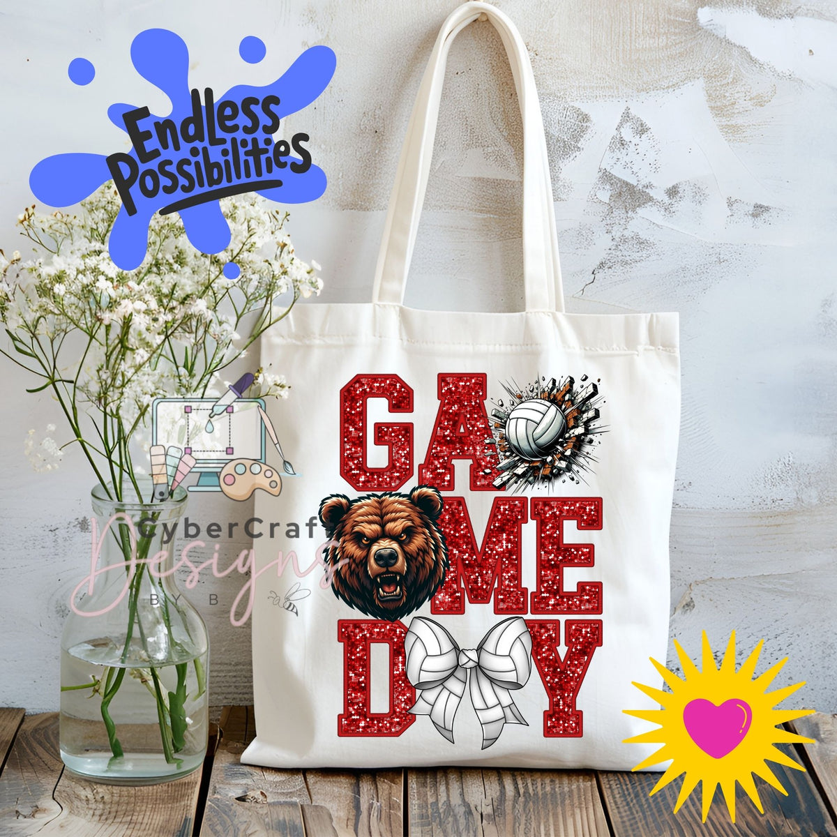 A white canvas tote bag with 'GAME DAY' printed in red glitter-style letters, featuring a bear head graphic, a volleyball, and a bow. The bag is displayed on a wooden surface next to a vase of white flowers, with decorative digital overlays including 'Endless Possibilities' and 'CyberCraft Designs'.